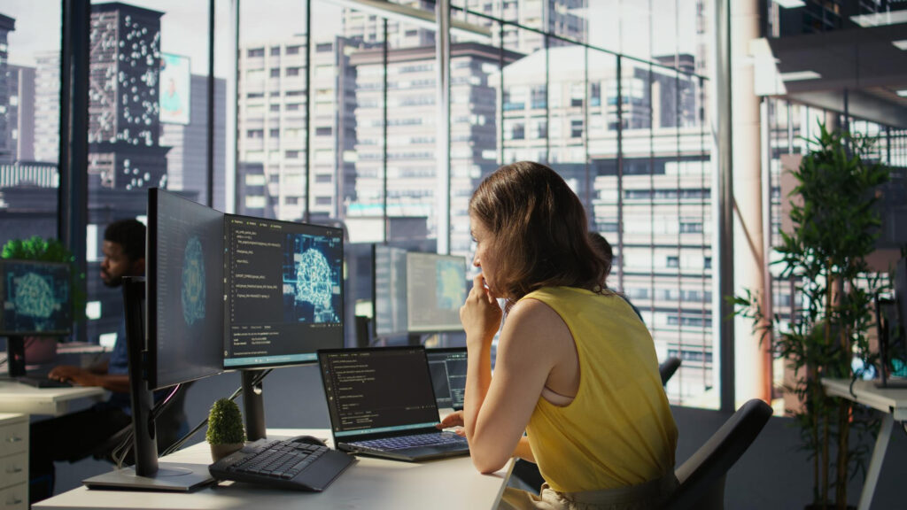 Mujer trabajando en ciberseguridad en una gran corporación empresarial.