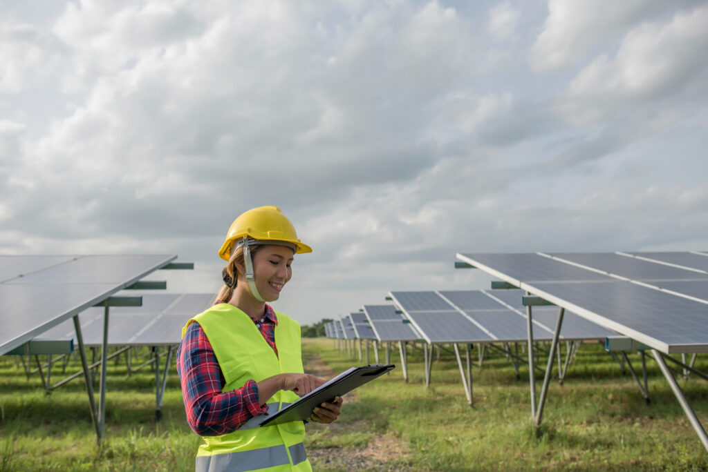 Mujer revisando la instalación de paneles fotovoltaicos en un descampado.